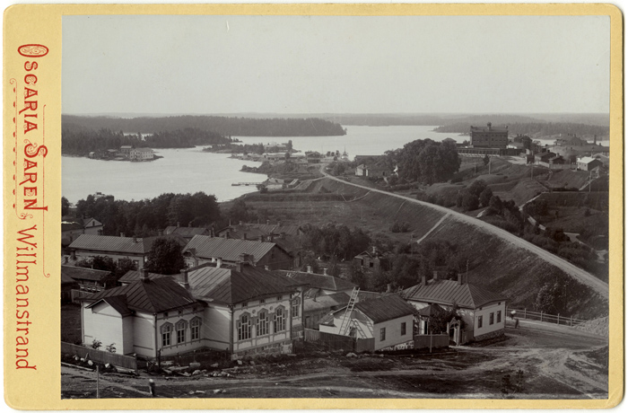Vanhassa valokuvassa 1890-luvulta näkyy maisema Nikolain valleilta Lappeenrannan linnoituksen suuntaan. Valokuva on liimattu keltaiselle pahville, jossa on punaisella paineittuna valokuvaajan - neiti Oscaria Sarénin sekä Lappeenrannan kaupungin nimi ruotsin kielellä.